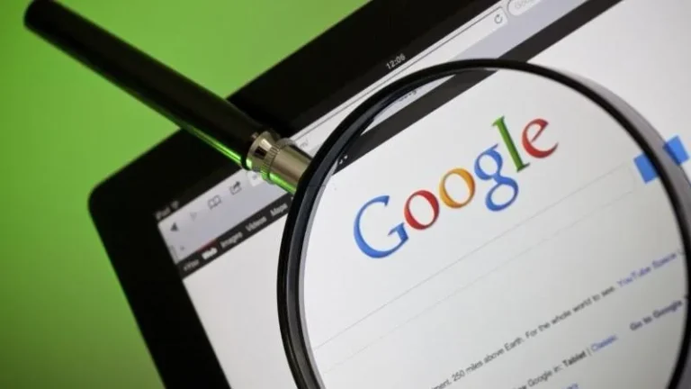 Magnifying glass over Google lettering beside a laptop keyboard